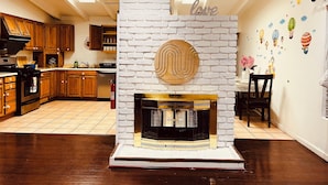 Eine moderne Küche mit Holzausstattung, einem eingebauten Backofen und einem weißen Kamin aus Ziegelsteinen, darüber ein dekoratives Wandelement.