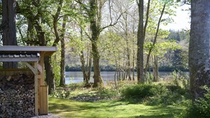 A wooden cabin with a gravel path leading to a lake, surrounded by trees and greenery. - Lochside hideaway with hot tub by Loch Ness (Inverness)