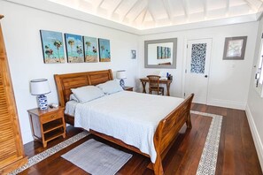 Un dormitorio con una cama de madera, mesitas de noche, un escritorio y obras de arte en las paredes.