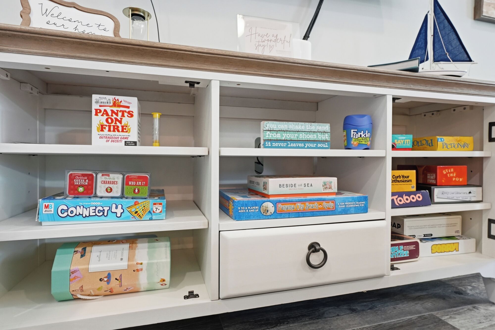 A bookshelf with various board games and a small sailboat decoration.