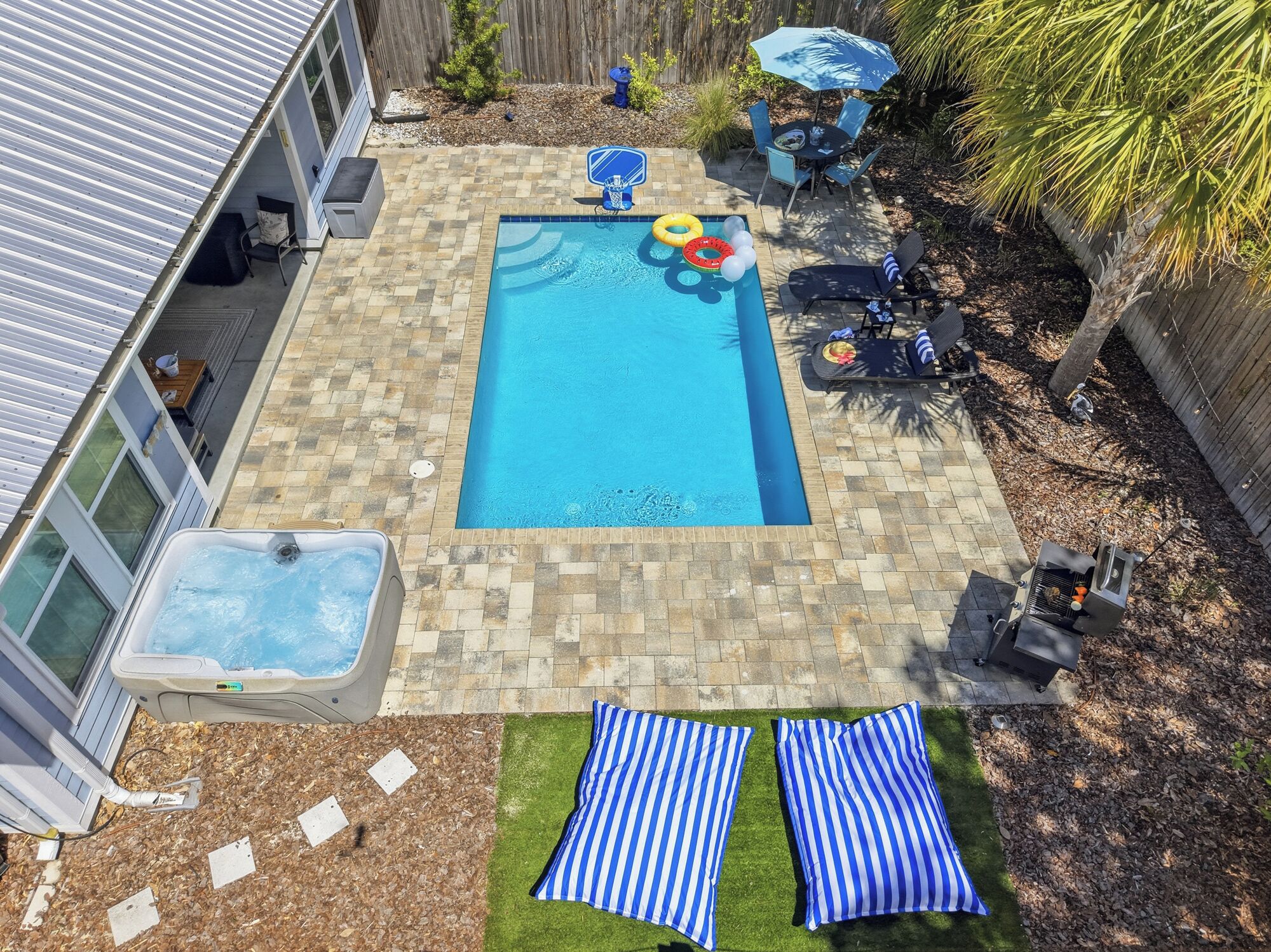 Un jardin avec une piscine, un jacuzzi et un espace barbecue.