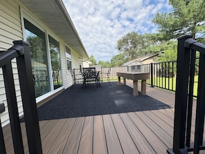 A deck with a table and chairs, a wooden fence, and a house in the background.