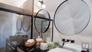 A modern bathroom with two sinks, a large mirror, and a glass shower enclosure. - Cupulas Del Valle  (Valle de Guadalupe)