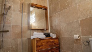 Een badkamer met een houten wastafel, een spiegel, een handdoekrek en een douche.