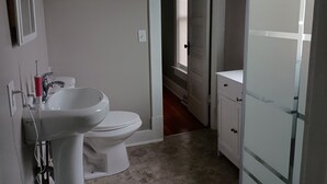 A bathroom with a toilet, sink, and cabinet. - Cozy 2-bedroom cottage in charming Council Bluffs with AC (Council Bluffs)