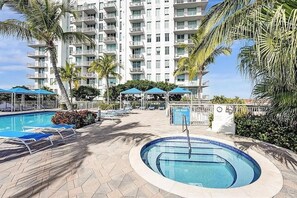 Un espace piscine d’hôtel avec des chaises longues, des parasols et un panneau indiquant les règles du spa.