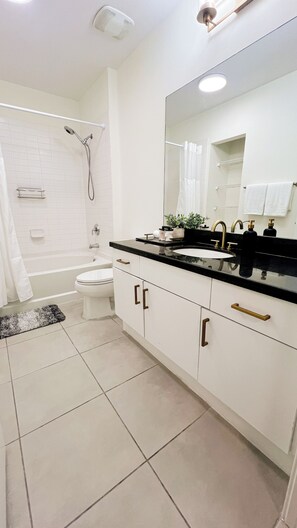 Une salle de bain moderne équipée d’une baignoire, de toilettes et d’un meuble-lavabo avec un grand miroir.