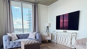 Ein modernes Wohnzimmer mit einem Ecksofa, einem Hocker und einem flachbildfernseher an der Wand.