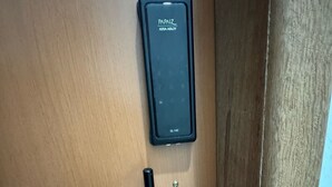En dörr med en kortläsare märkt "PAPAIZ ASSA ABLOY SL140" och en hållare för nyckelkort.