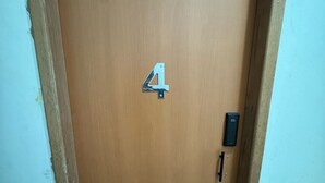 En dörr av trä med en skylt med siffran ’4’, ett dörrhandtag och en liten elektronisk apparat på höger sida.