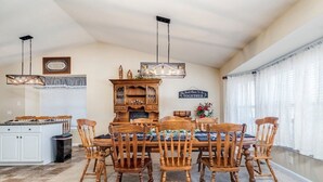Un comedor con mesa y sillas de madera, un candelabro y un aparador con un cartel de 'Welcome'.