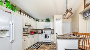 Una cocina con armarios blancos, encimera de granito, alfombra a cuadros negros y blancos, y un letrero que dice 'PANTRY'.