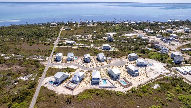 An aerial view of a coastal resort with multiple buildings, a central pool area, and a road leading to the beach. - Heated Salt Pool | Walk to Beach | Lowered Rates | Firepit (Port St. Joe)