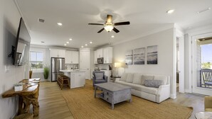 A spacious living area with a kitchen, a dining table, a sofa, and a ceiling fan. - Heated Salt Pool | Walk to Beach | Lowered Rates | Firepit (Port St. Joe)