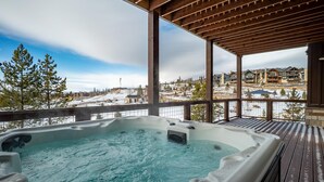 A hot tub on a wooden deck with a view of a snowy landscape and buildings. - Rendezvous 4BR Retreat | New Hot Tub, Mtn Views (Winter Park)