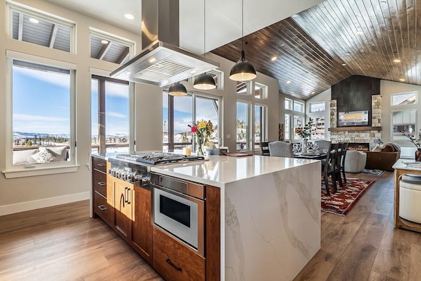 A spacious kitchen with a large island, built-in oven, and a view of a snowy landscape. - Luxury Mountain Home • Views + Hot Tub (Winter Park)