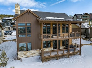 A multi-story building with large windows, a balcony, and a snow-covered ground. - Luxury Mountain Home • Views + Hot Tub (Winter Park)