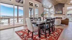 A spacious dining area with a large table set for six, surrounded by chairs, and a red patterned rug on the floor. - Rendezvous 4BR Retreat | New Hot Tub, Mtn Views (Winter Park)