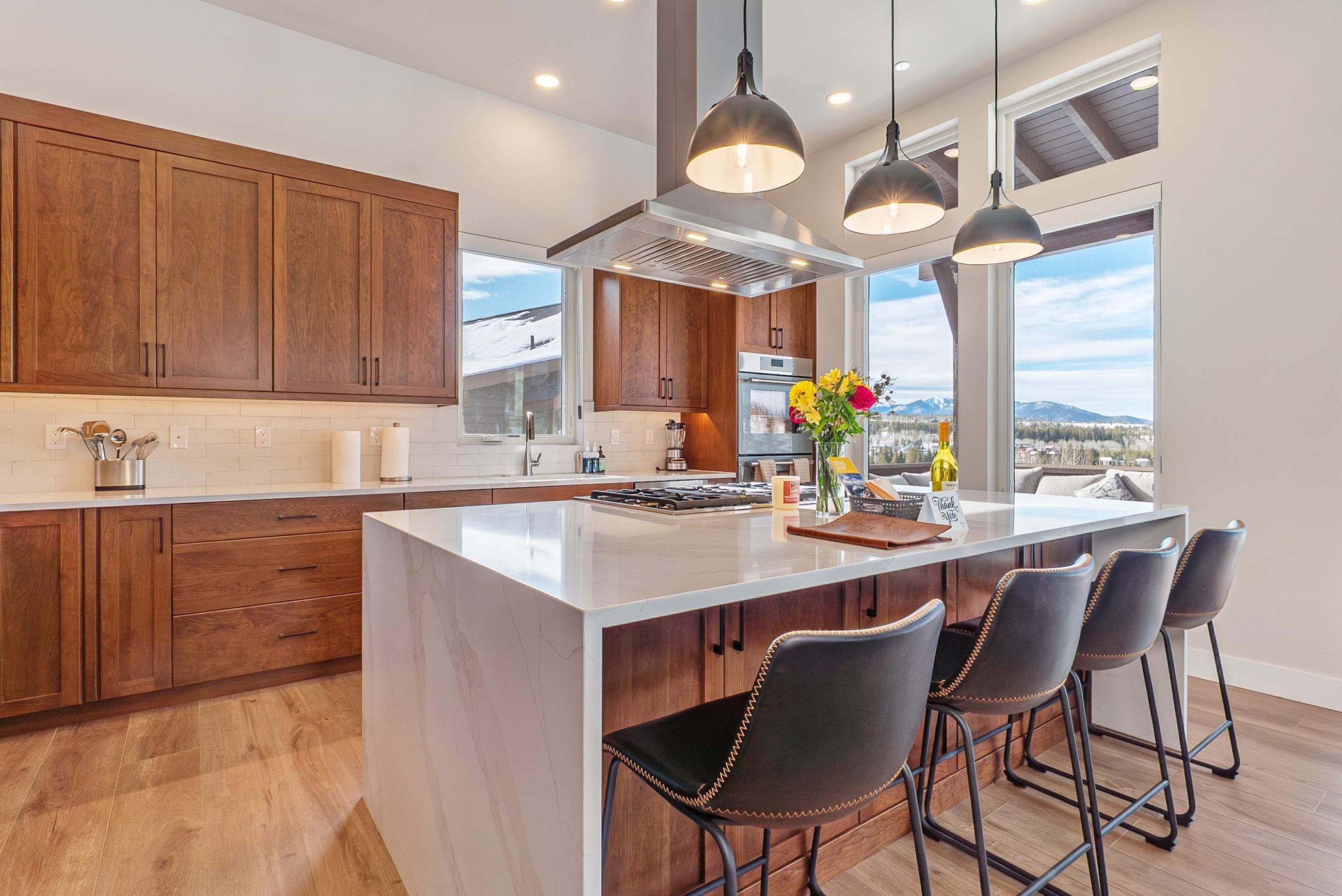 A modern kitchen with a large island, wooden cabinets, and bar stools.