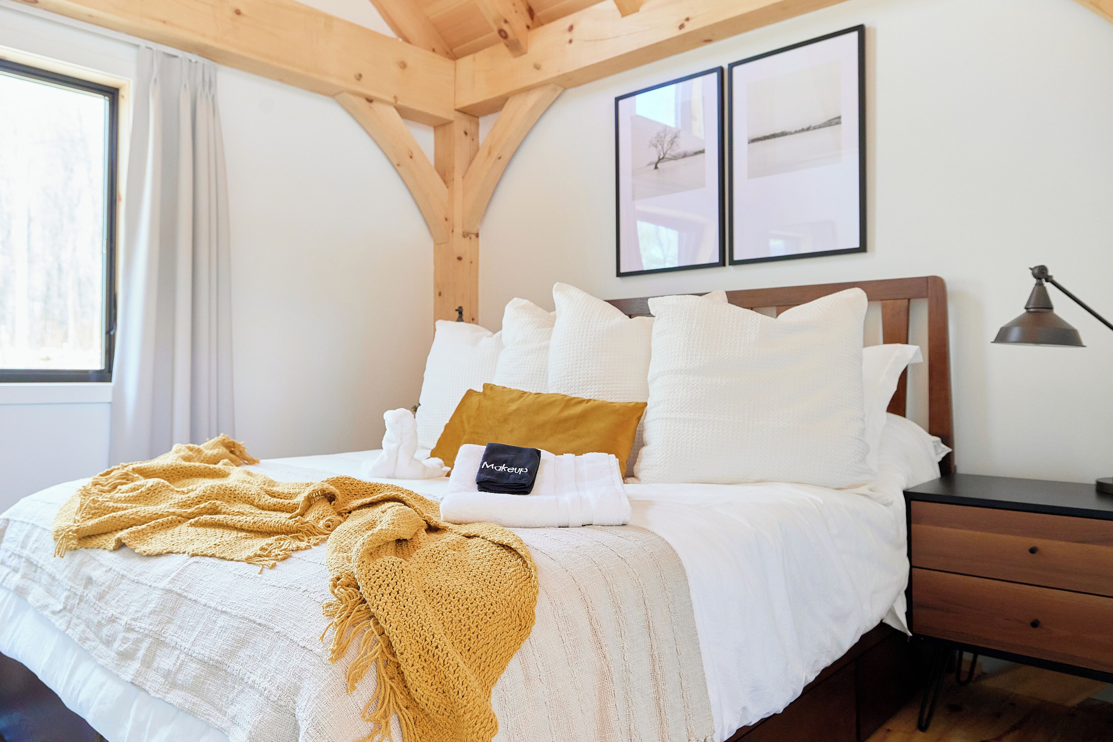 A bedroom with a bed, a nightstand, a lamp, and framed pictures on the wall.