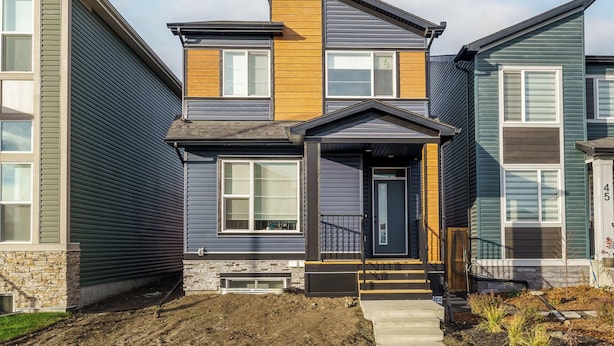 A two-story house with a stone foundation, a front porch, and a small front yard. - CozyWolf (New 2 Bedroom Suite) (Calgary)