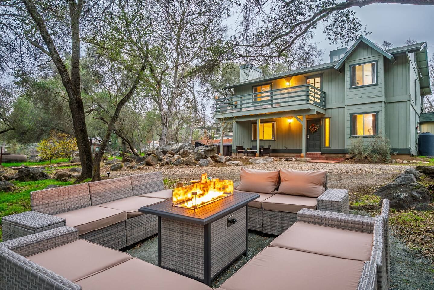 Eine Terrasse mit Feuerstelle, Sitzgelegenheiten im Freien und einem Haus im Hintergrund.