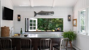 Une cuisine avec une grande sculpture de poisson, un téléviseur et une fenêtre donnant sur un espace verdoyant.