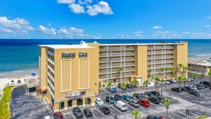 Ein Hotel mit großem Parkplatz, mehreren Etagen und Blick auf den Strand.