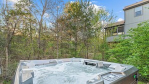 Un jacuzzi al aire libre rodeado de árboles y un edificio.