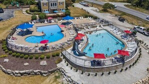 Un resort con dos piscinas, un área de juegos y un edificio grande de fachada de piedra.