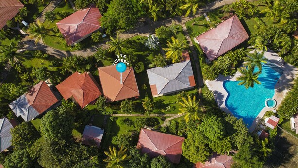 Ein Luftbild eines Resorts mit mehreren Gebäuden, einem Swimmingpool und üppiger Vegetation.