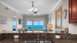 A kitchen with granite countertops, a double sink, a ceiling fan, and a view of the ocean. - 18th Floor!  Indoor/Outdoor Pools. Free Daily Activities + Beach Service (Gulf Shores)