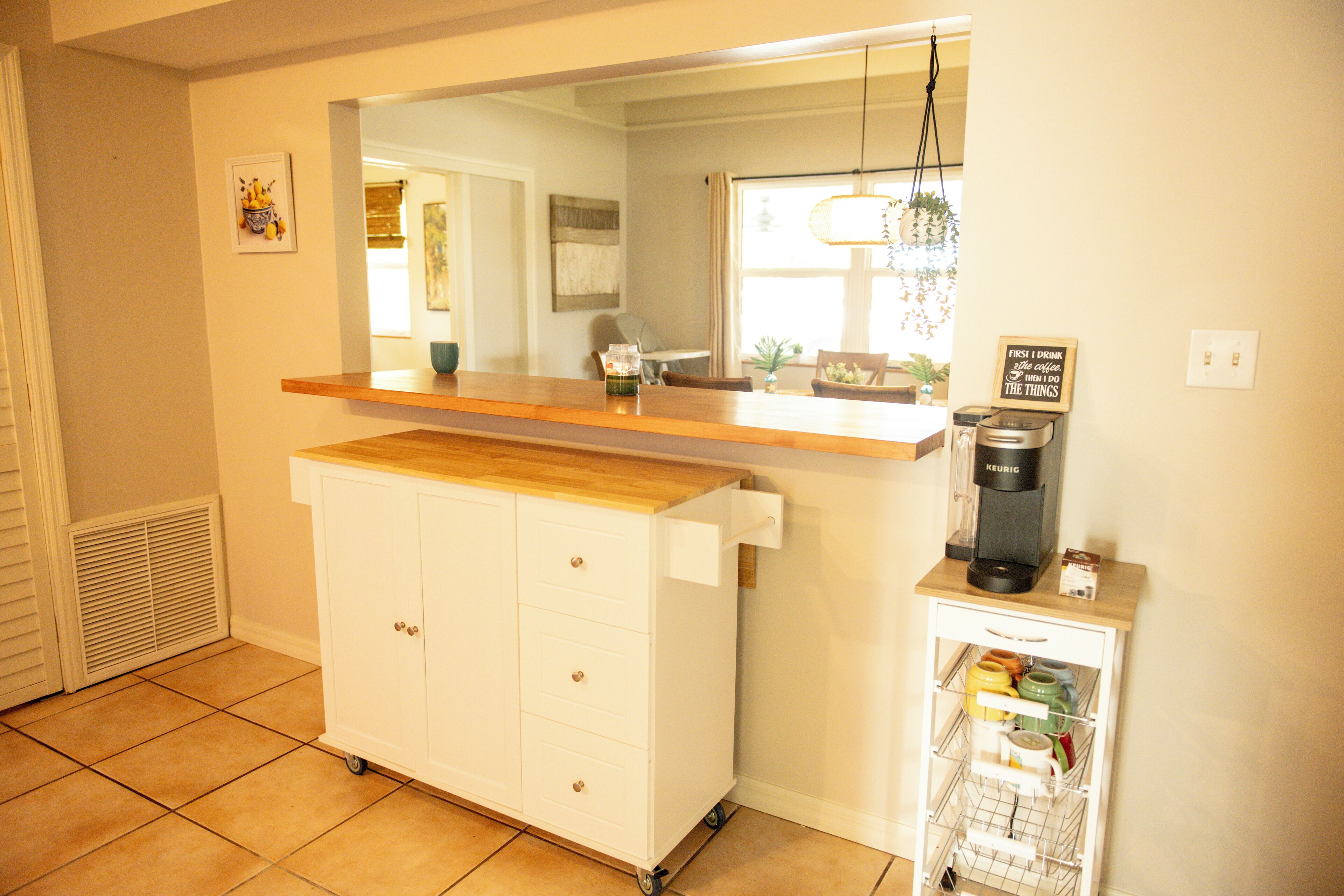 A kitchen with a wooden countertop, a coffee maker, and a storage cart.