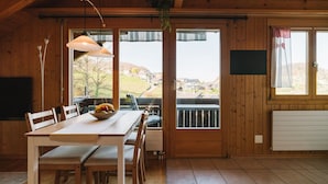 Un comedor de madera con una mesa, sillas y un cuenco de fruta.