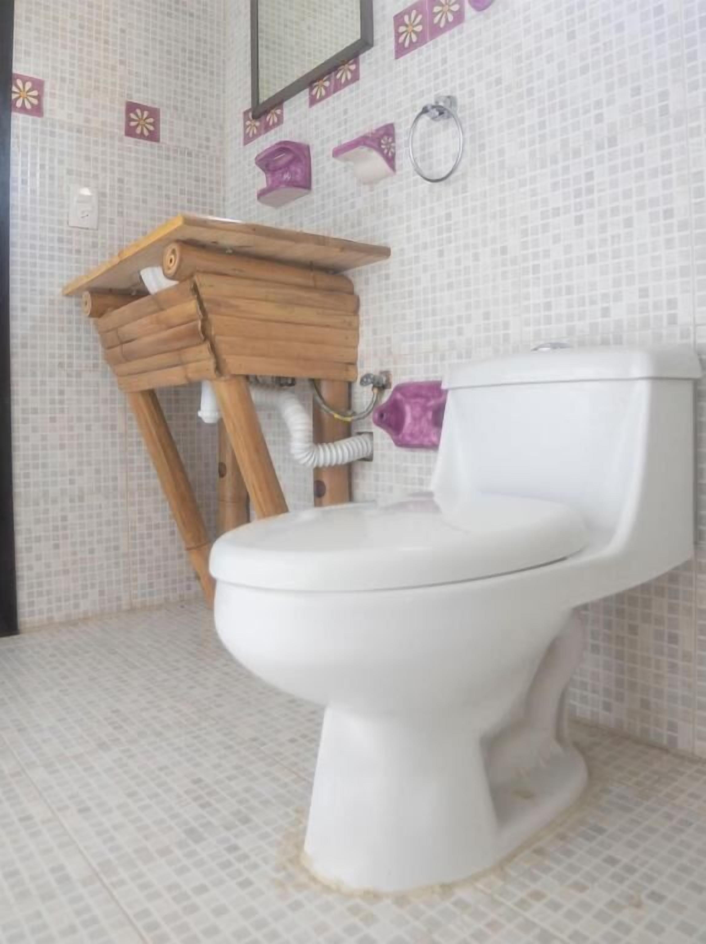 A bathroom with a white toilet, a wooden vanity with a mirror, and a tiled floor.