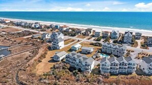 A coastal residential area with houses, a beach, and a clear sky.