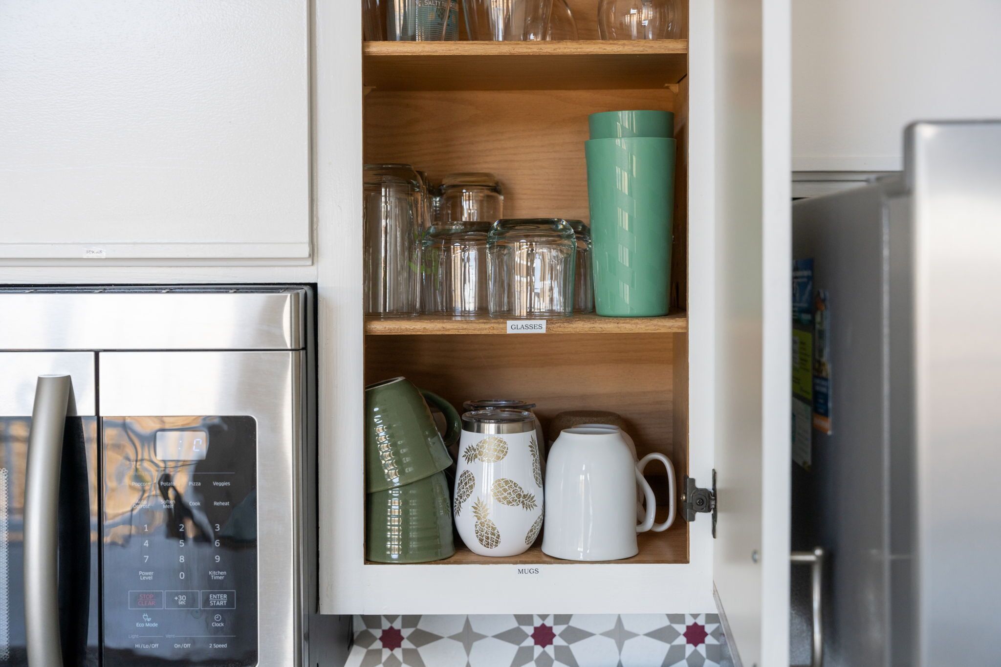 Un meuble de cuisine contenant de la verrerie, des tasses et un four à micro-ondes.