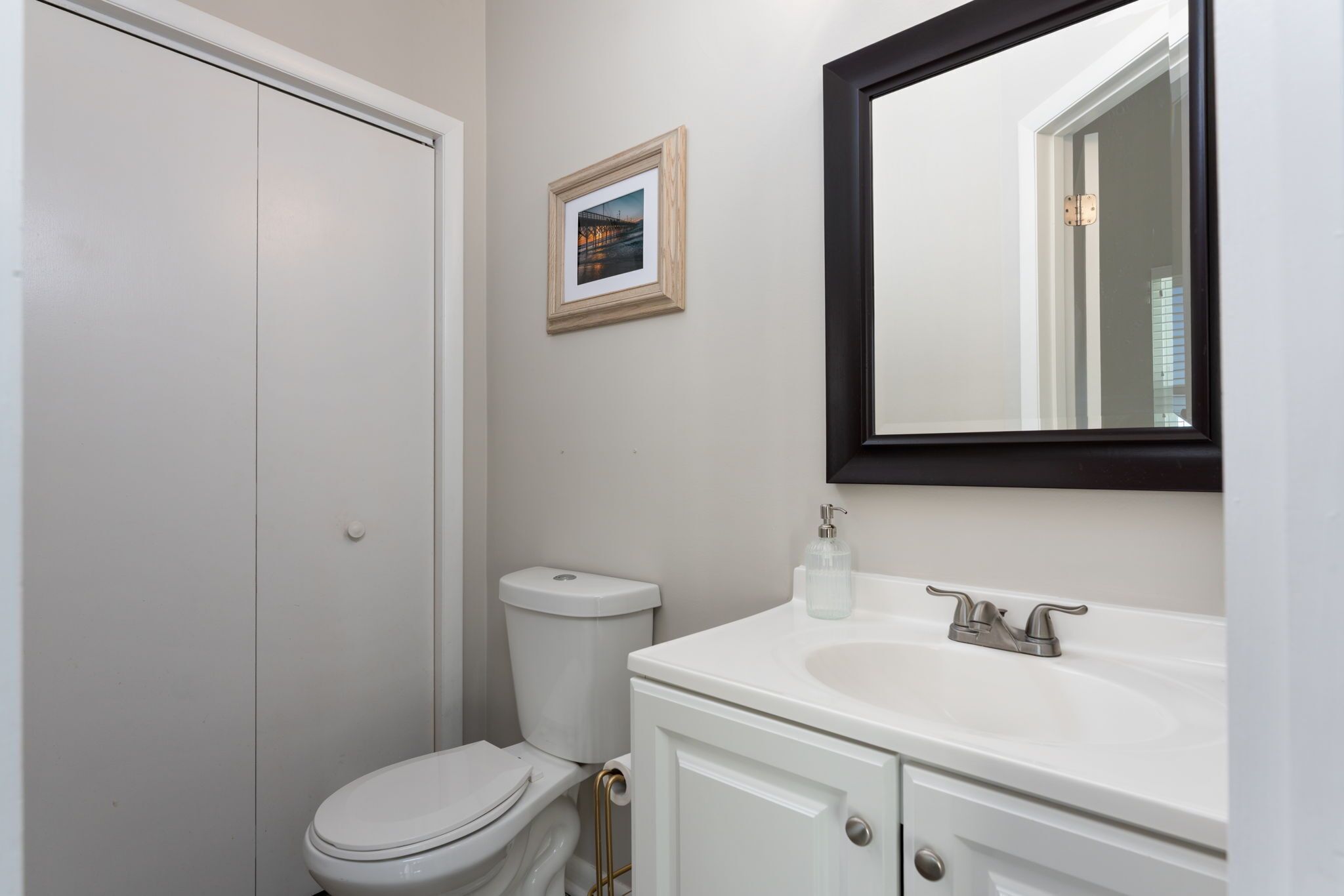 A bathroom with a toilet, sink, and mirror.