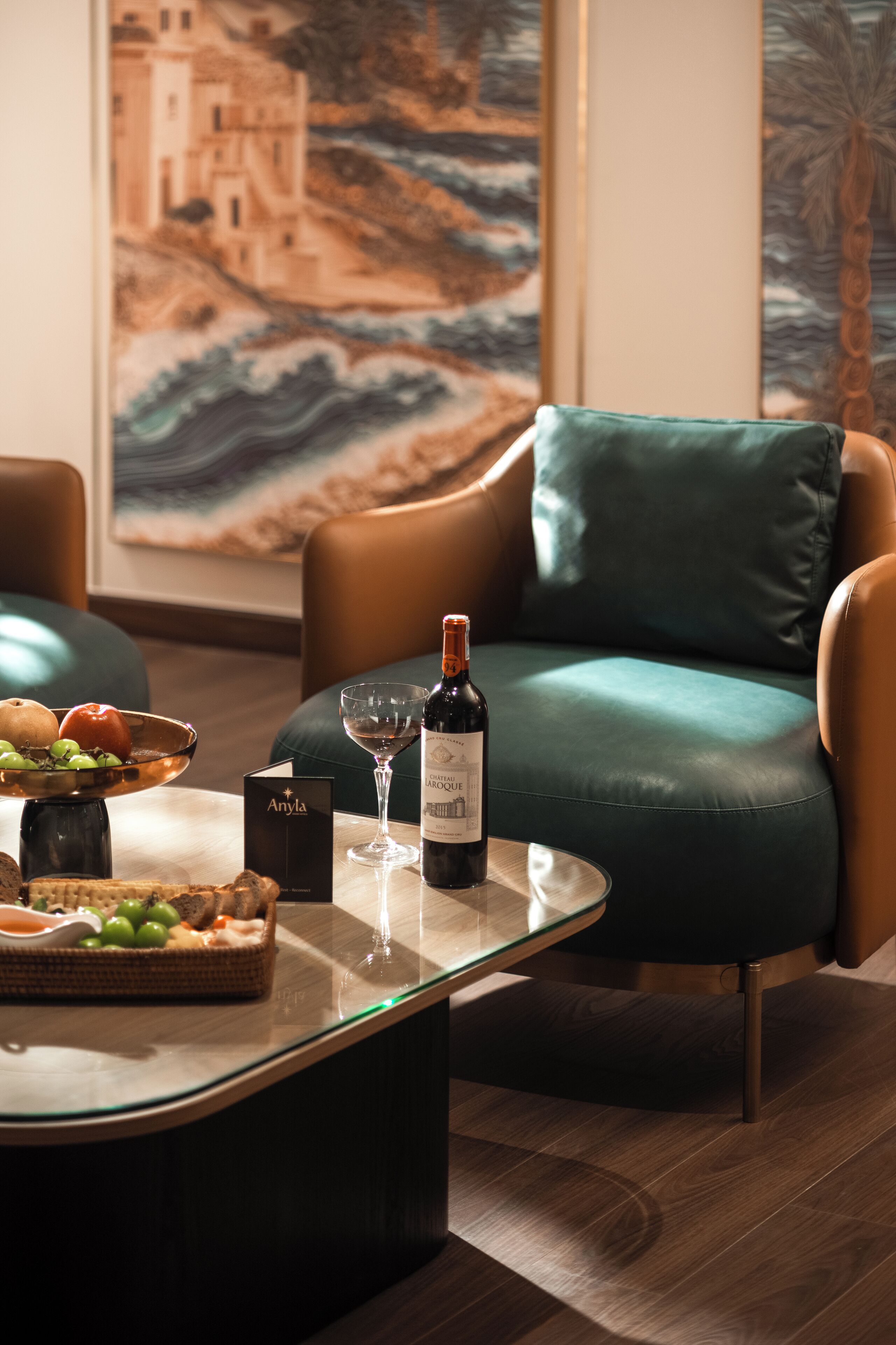 A modern living room with a leather sofa, a glass coffee table, and a wine bottle.
