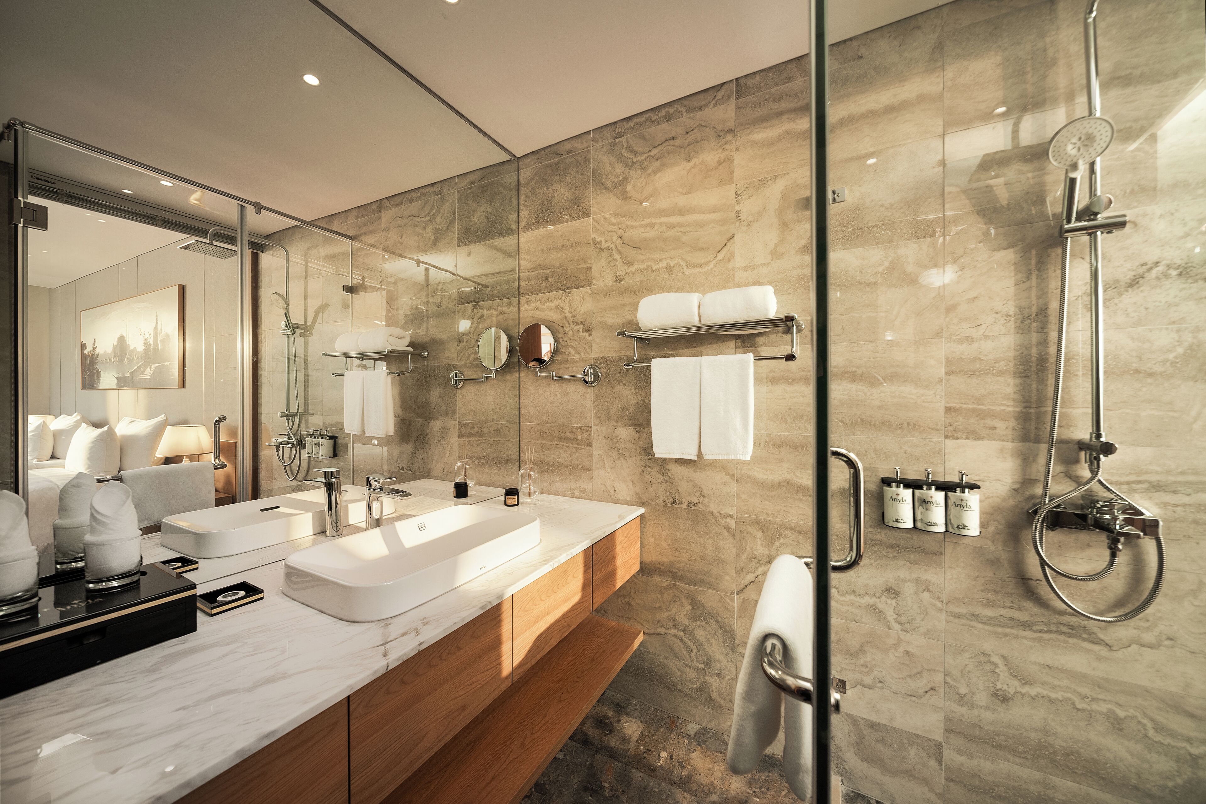 Un baño moderno con ducha envuelta en vidrio, tocador doble y espejo grande.