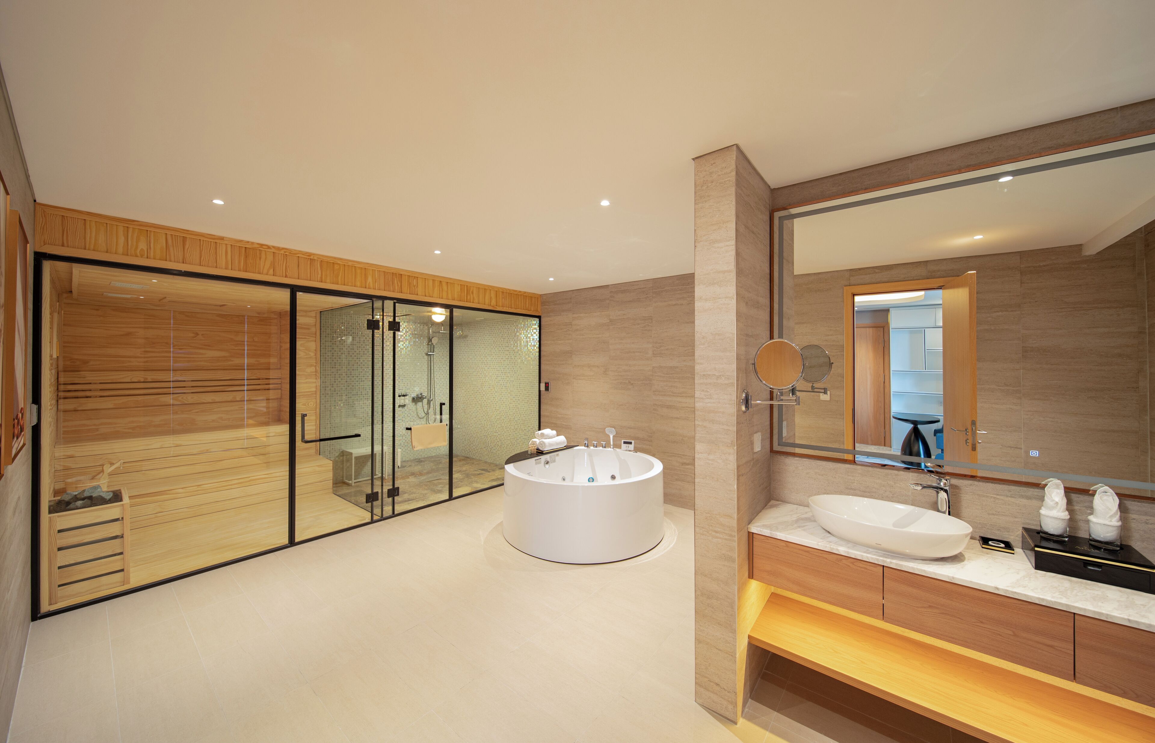 A modern bathroom with a large bathtub, a vanity with a sink, and a large mirror.