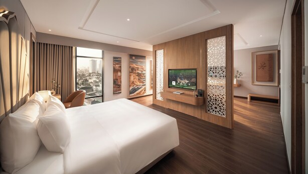 Une chambre d’hôtel moderne dotée d’un grand lit, d’un téléviseur à écran plat, d’une vue sur la ville et d’une cloison décorative.