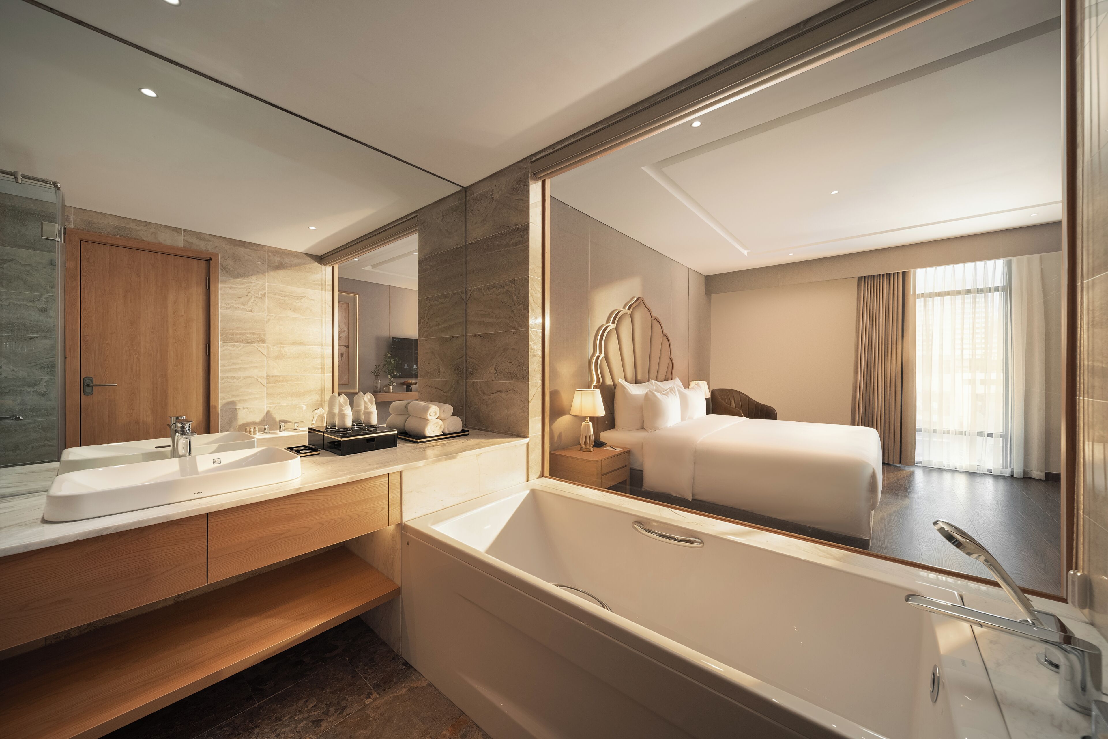 A modern bathroom with a large mirror, a bathtub, a vanity with a sink, and a wooden door.