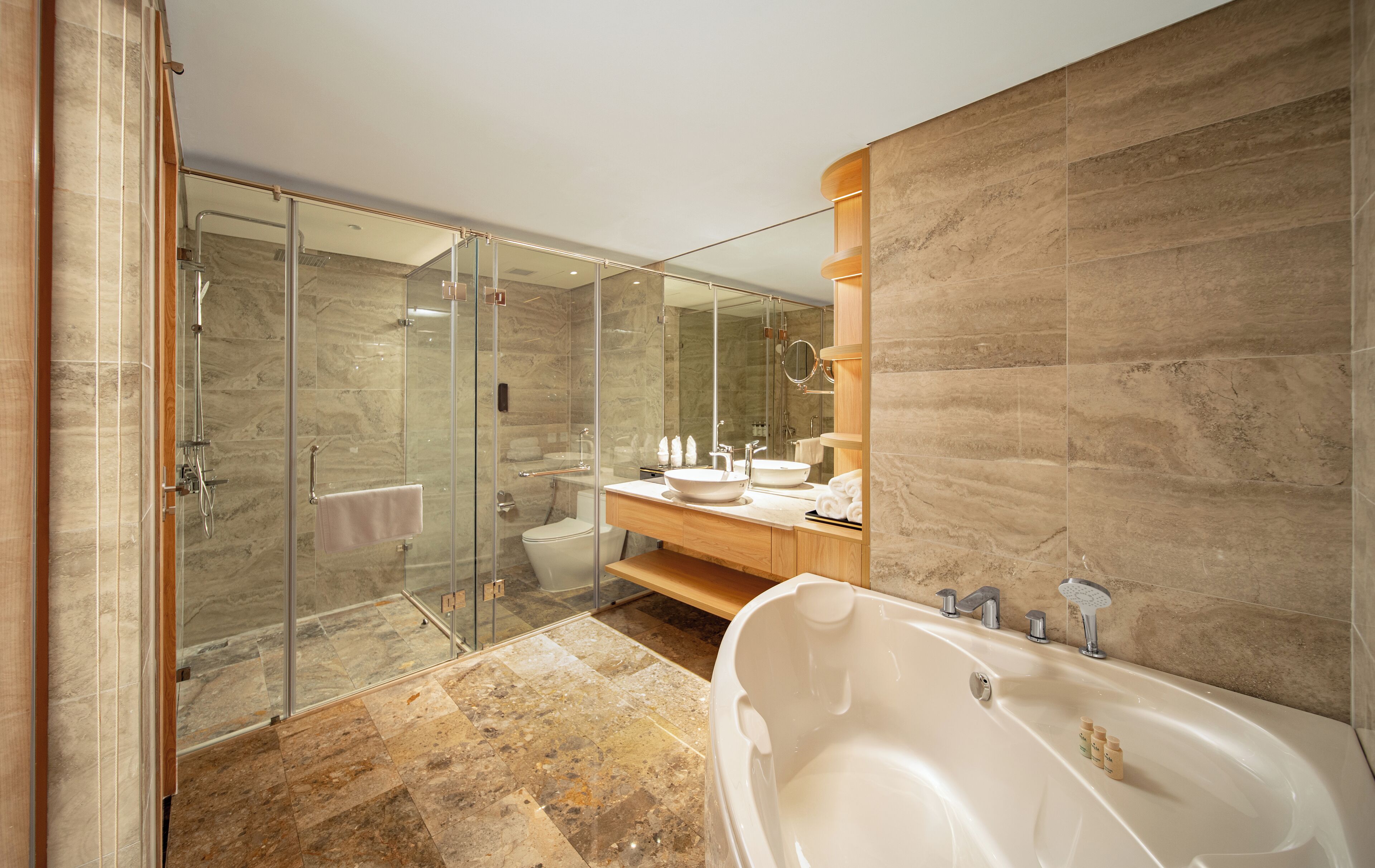 A modern bathroom with a glass-enclosed shower, a freestanding bathtub, and a vanity with a large mirror.