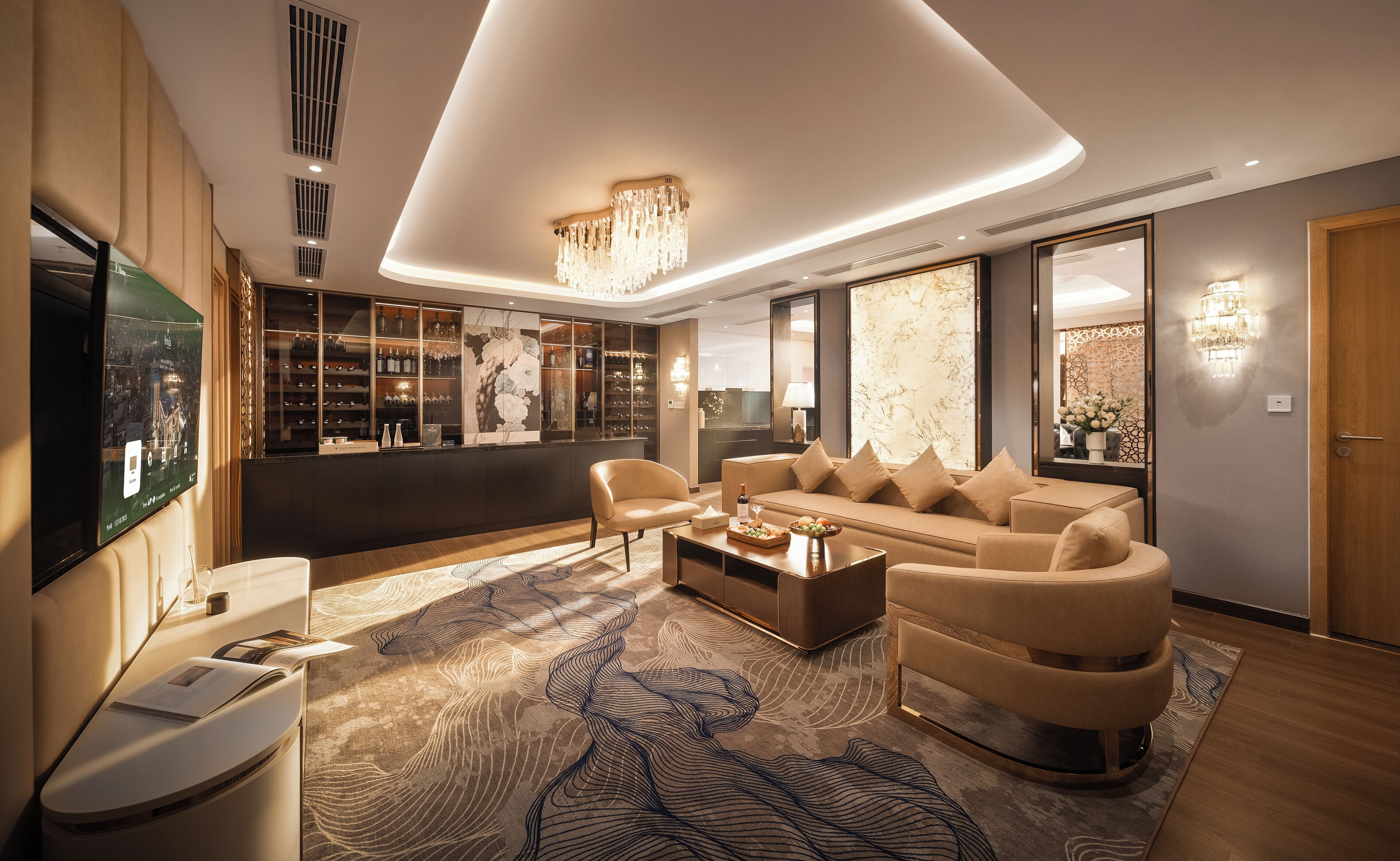 A modern living room with a large flat-screen TV, a bar area with shelves of bottles, and a large sofa.