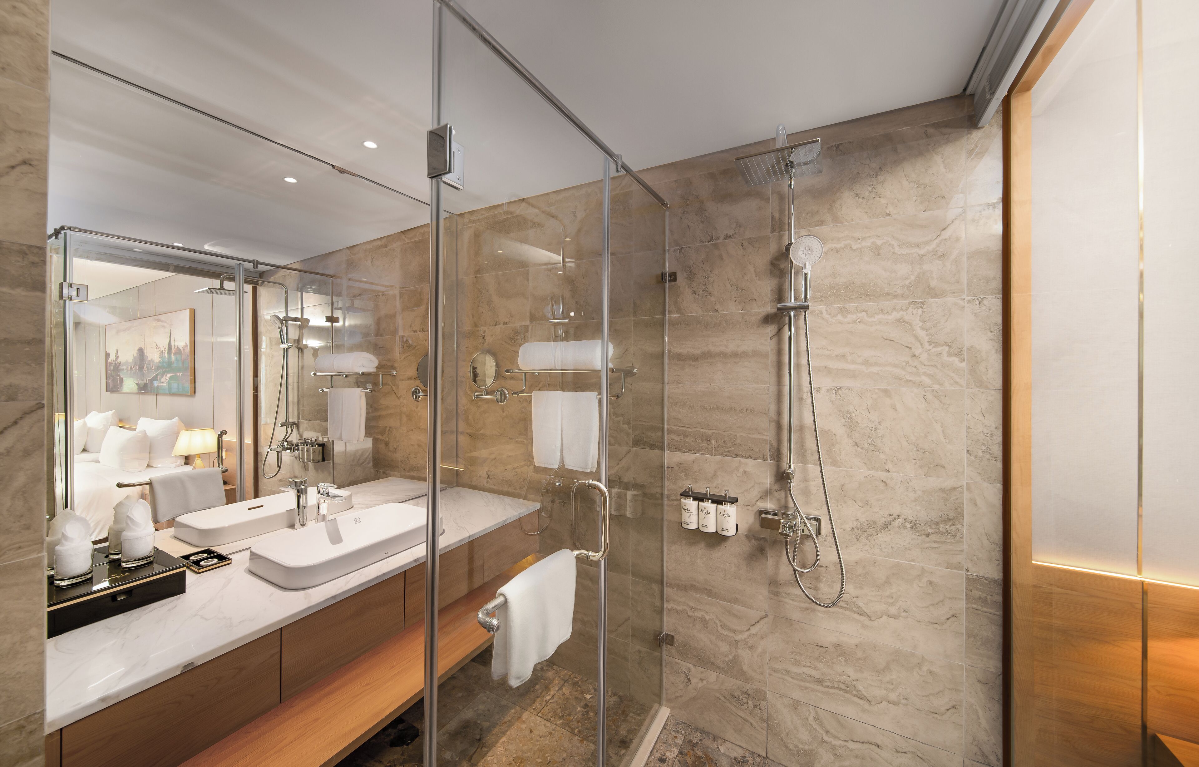 Un baño moderno con ducha envuelta en vidrio, un espejo grande y un tocador de madera.