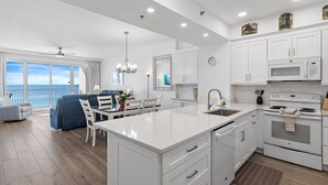 Una cocina moderna con armarios blancos, una isla grande y vista al océano.