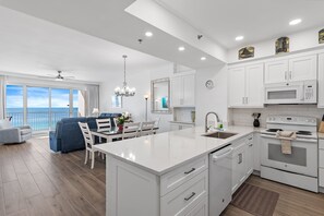 A modern kitchen with white cabinetry, a large island, and a view of the ocean. - Beach Front Unit-Tops'l Resort-Pickleball Courts-Covered Parking-Tides 804 (Miramar Beach)