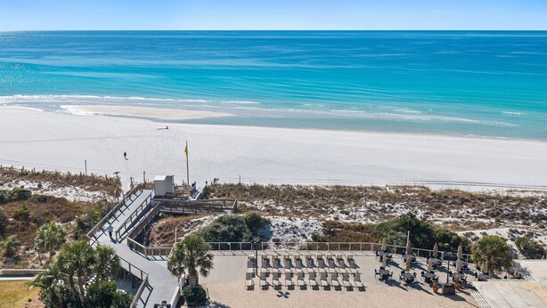 Un resort frente al mar con un paseo marítimo, sillas de playa y sombrillas.