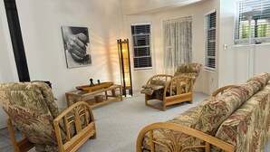 Ein Wohnzimmer mit einer Couch, zwei Sesseln, einem Couchtisch und einem Wandbild.